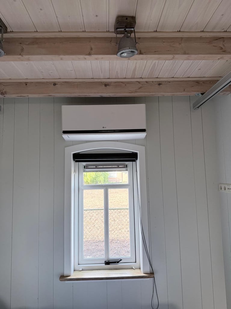 Interior room with wooden beam ceiling, white shiplap walls, a window with white frame, and a split AC unit mounted above
