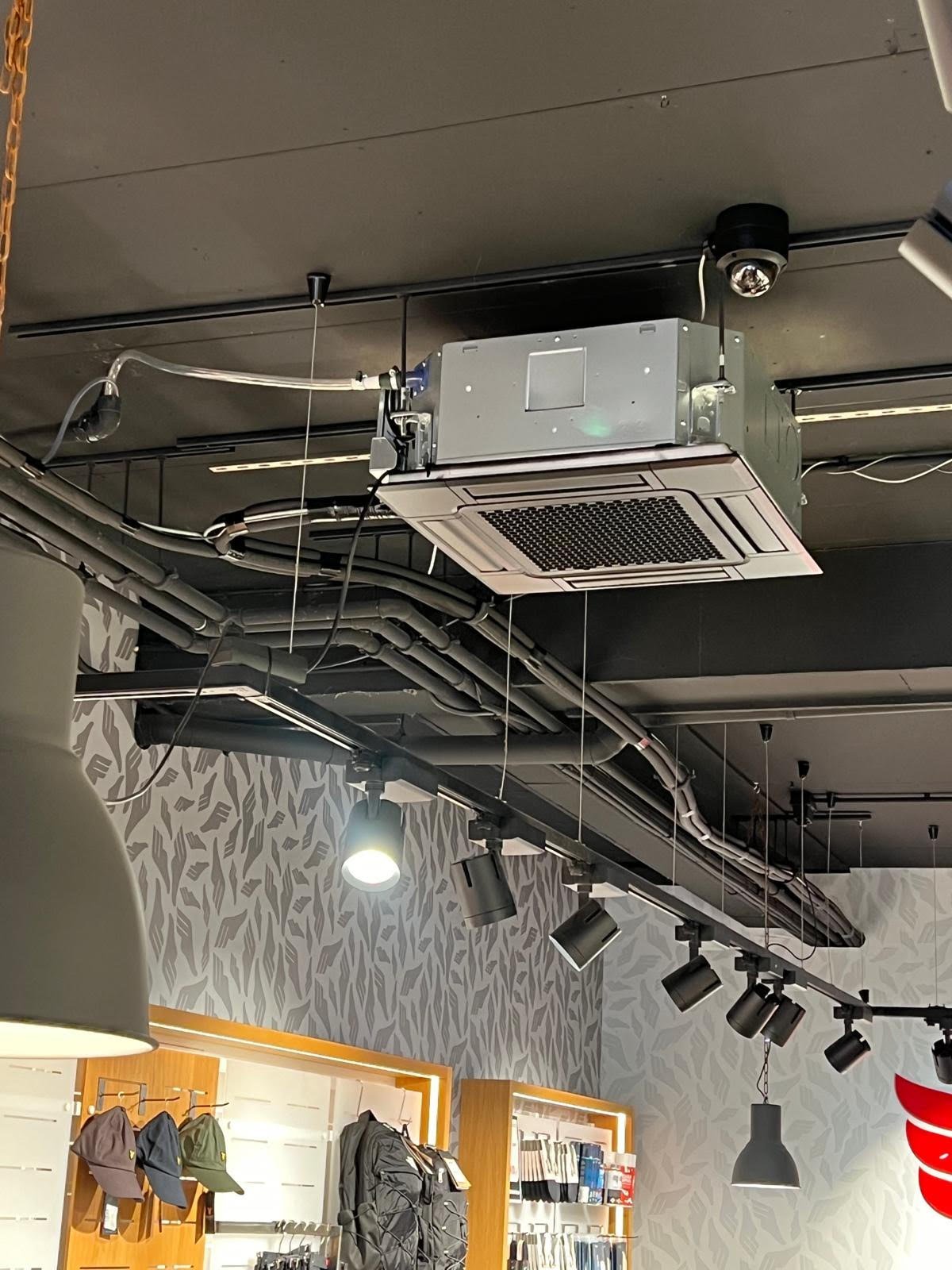 Ceiling-mounted HVAC unit and track lighting system with ductwork and cable management in commercial interior space