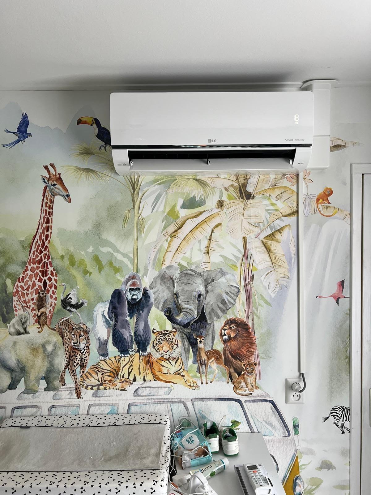 Bedroom wall mural featuring various wild animals including giraffe, lion, elephant, and tiger, with a white air conditioning unit mounted above