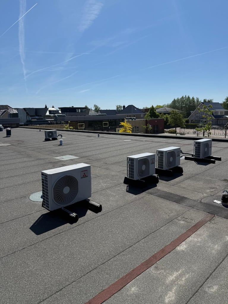 HVAC units installed on a flat roof with residential homes and trees visible in the background under clear blue sky